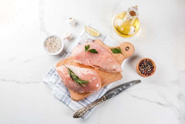 Raw meat, chicken breast filet, with olive oil, herbs and spices on white marble background, copy space top view